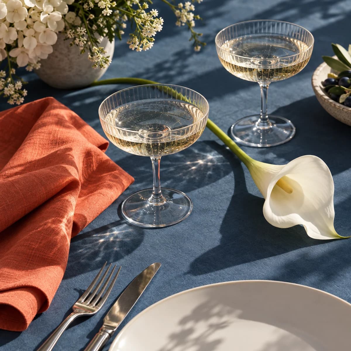 Wedding table with glasses, a white flower and an orange napkin